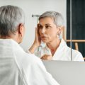 woman looking in the mirror thinking about J-Plasty facelift